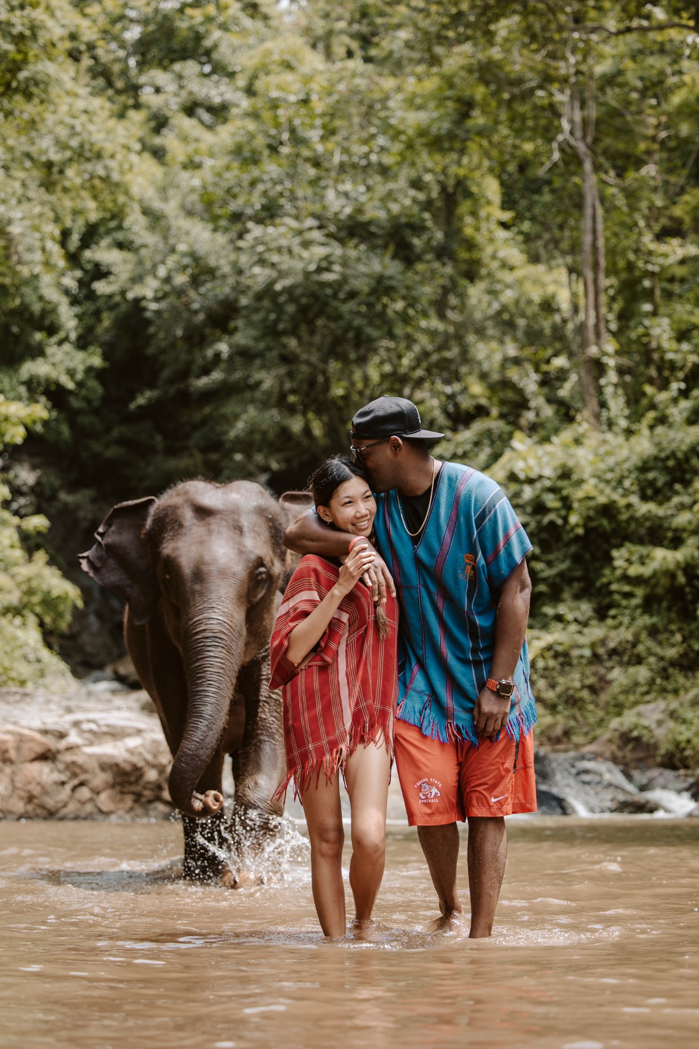 Stephanie and Quay walking together beside an elephant