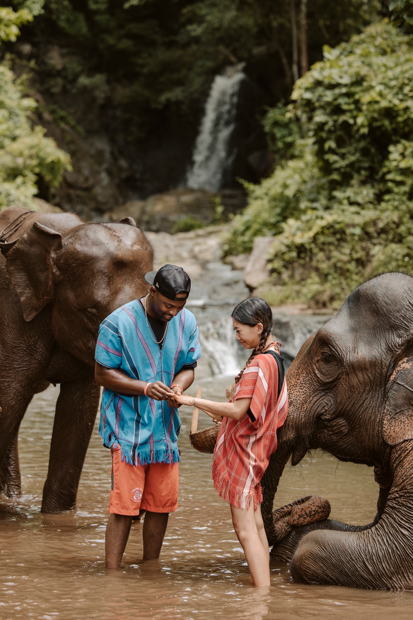 Stephanie and Quay standing with elephants in the river