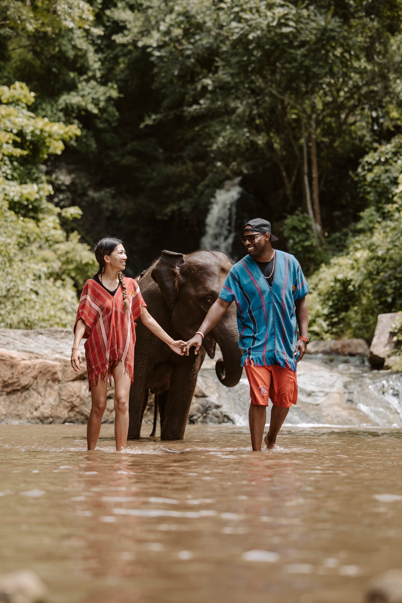 Stephanie and Quay holding hands with an elephant nearby