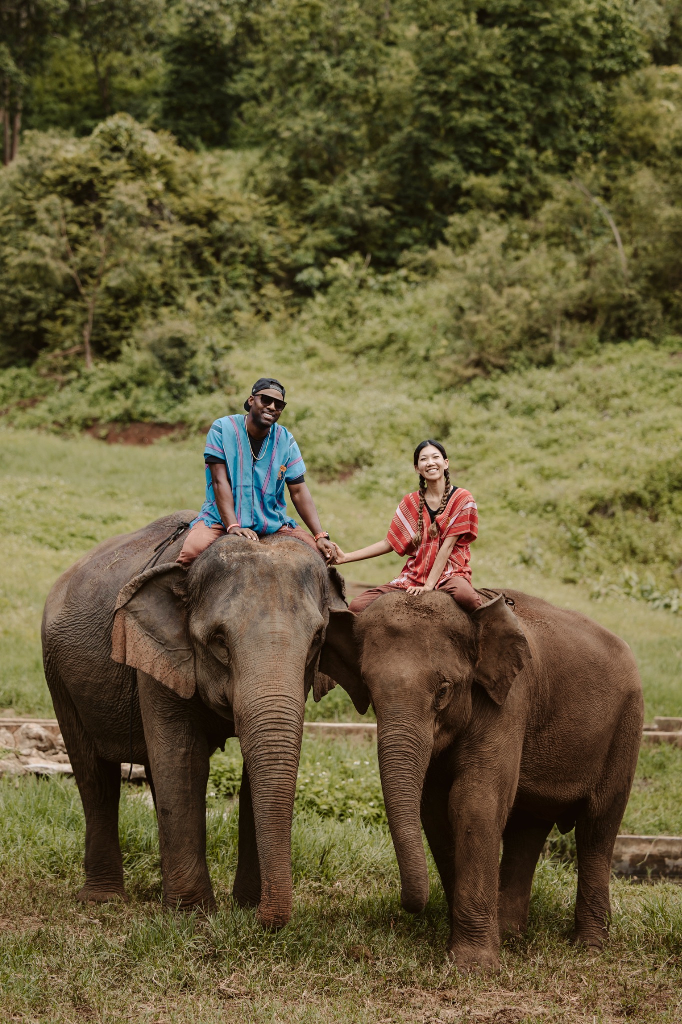 Stephanie and Quay riding alongside elephants